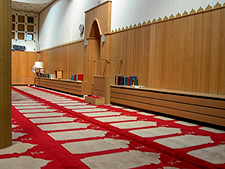 Gebetsraum mit rot-weißem Teppich vor holzvertäfelter Wand
