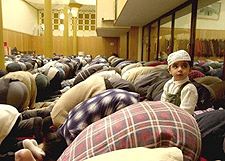 Muslime knien nieder beim Gebet, ein Kind kniet aufrecht