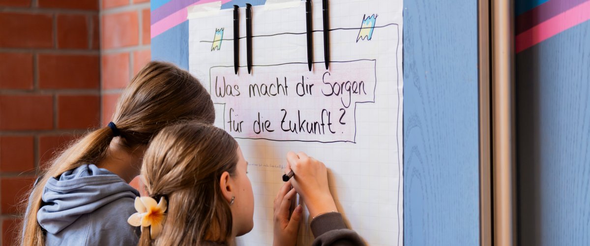 Two young people collect ideas on a flipchart on the topic "Worries in the future"