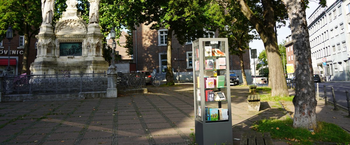 A bookcase in front of St. Jakob. Next to it a fountain. Copyright: City of Aachen