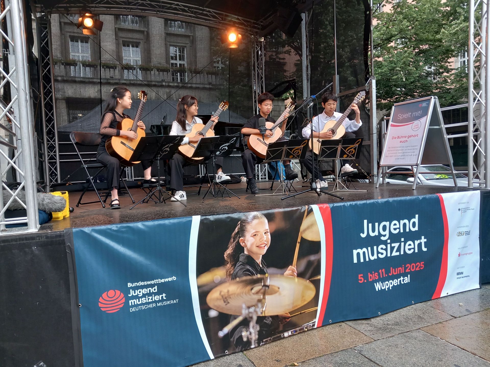 Four children play guitar on a stage at the Jugend musiziert competition in Wuppertal