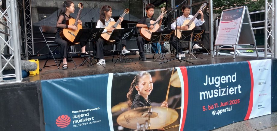 Four children play guitar on a stage at the Jugend musiziert competition in Wuppertal