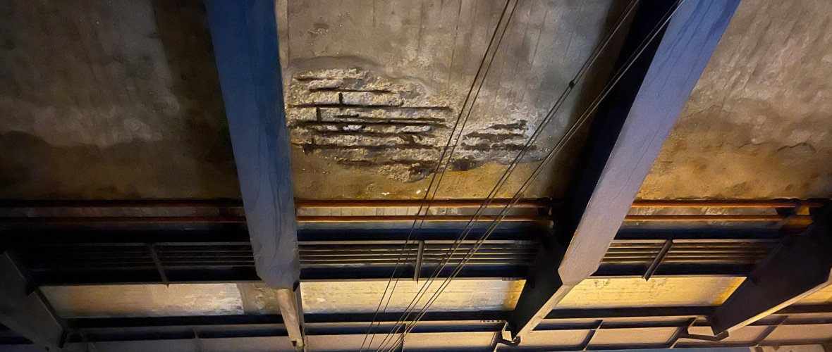 An exposed cavity with heavily corroded rebar beneath the bridge