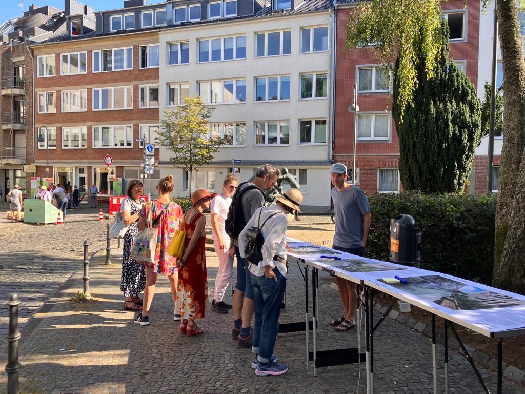 Participants in a public engagement process are learning about the redesign of Klappergasse and Rennbahn in Aachen on-site using a rendering