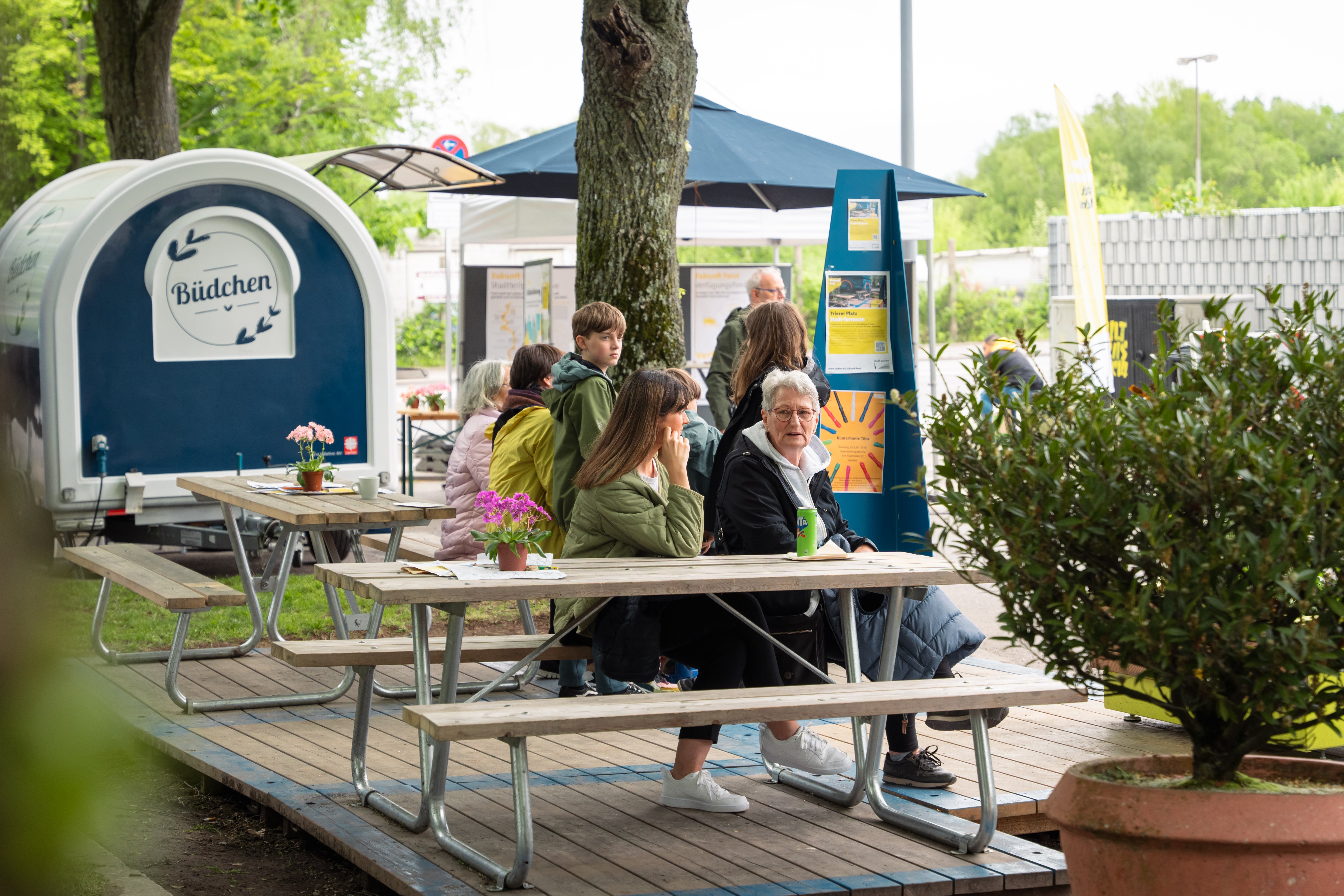 Two people sit together on a wooden bench and talk