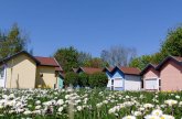 Small flowers bloom on the meadow in the foreground and the sky is bright blue. The various houses of the Florian village can be seen in the background.