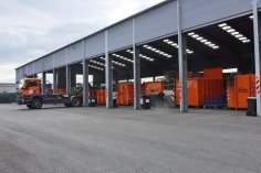 Eilendorf recycling center. A truck with a hook is parked in front of a large hall containing orange containers.