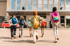 Group of schoolchildren running hurriedly to the school building .