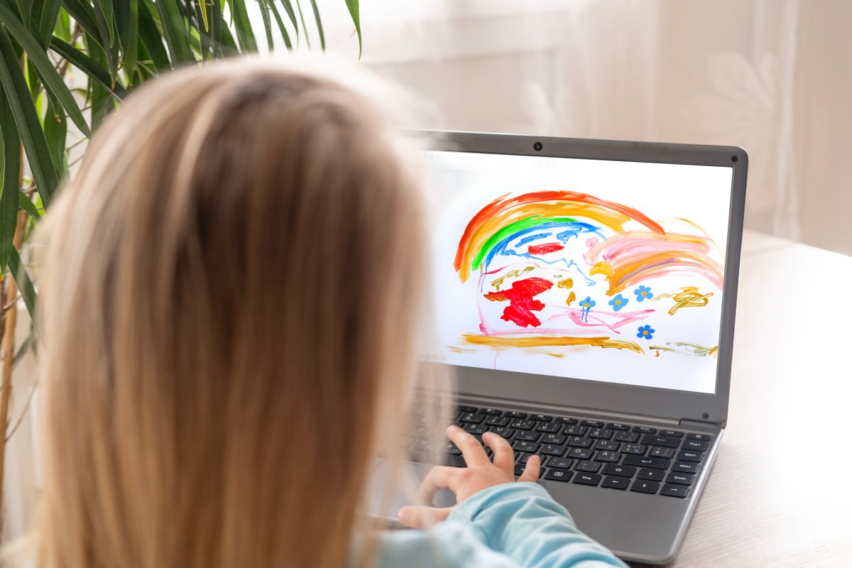 Preschool girl, 5 years old, draws elements on the laptop screen and learns digital skills through play.