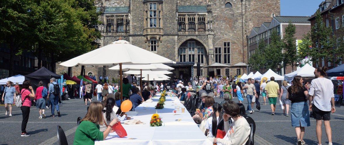 People sit at a long table on the cathedral cathedral with the cathedral in the background.