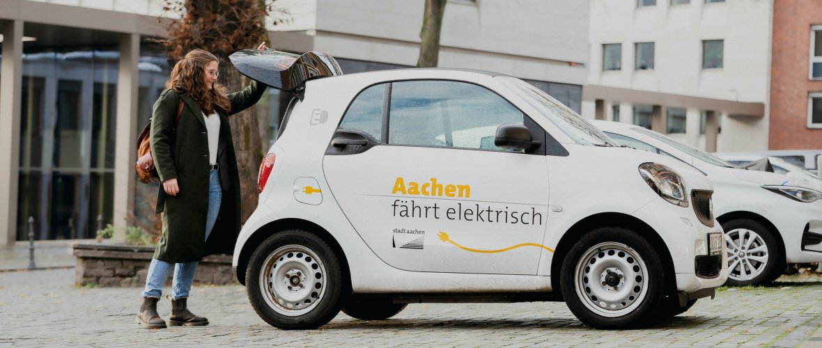 A woman charges an e-car from the Aachen fleet.