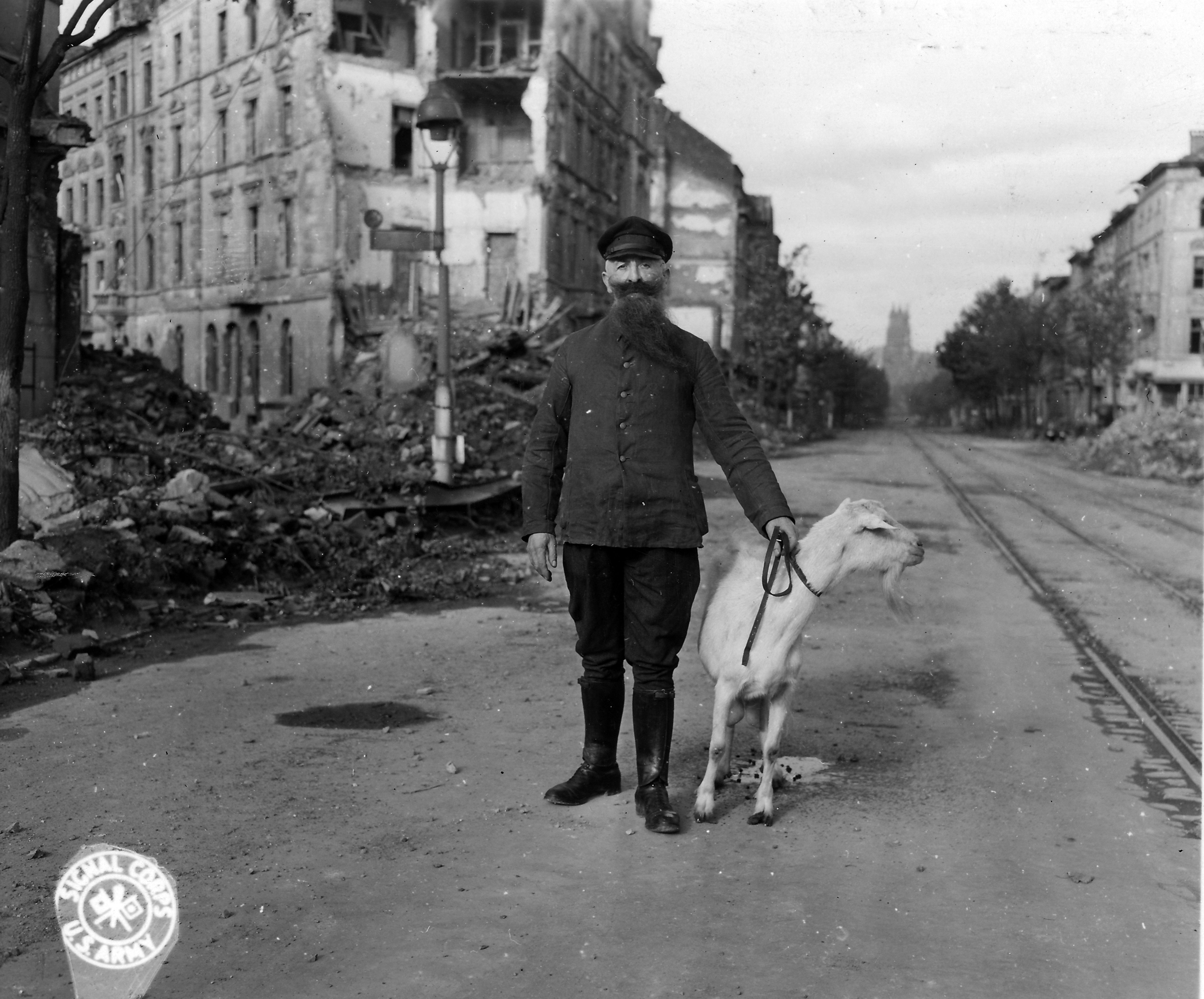 Historical picture of a man with a goat in front of a ruined city facade