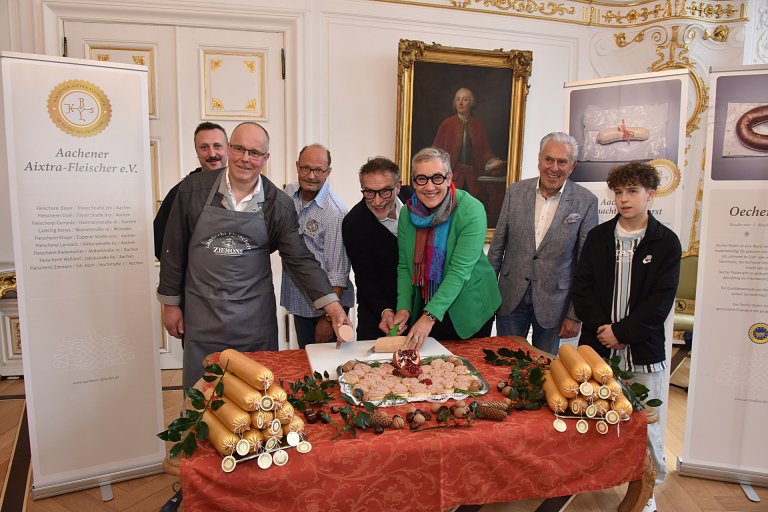 Rolf Gerrards and Lord Mayor Sibylle Keupen (center) cut the Aachen Christmas Liverwurst 2024 in the White Hall of the Town Hall.