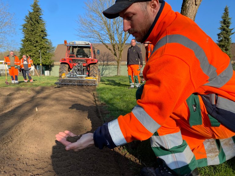 A man in work clothes scatters seeds in the soil