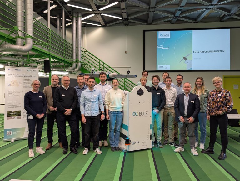 A group of people in the foyer of the University Hospital with a model of a drone
