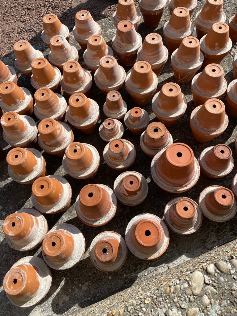 A row of clay pots standing upside down on the floor.
