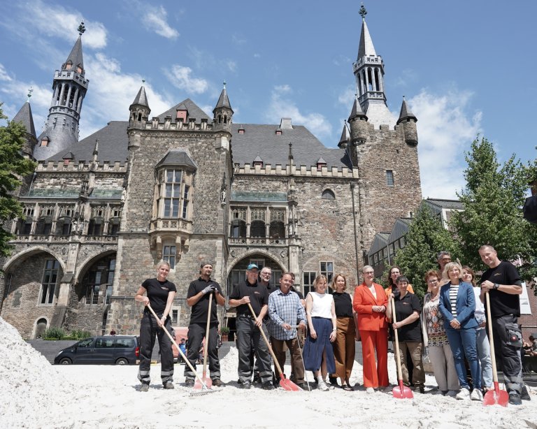 A group of people with shovels in a large sandpit.