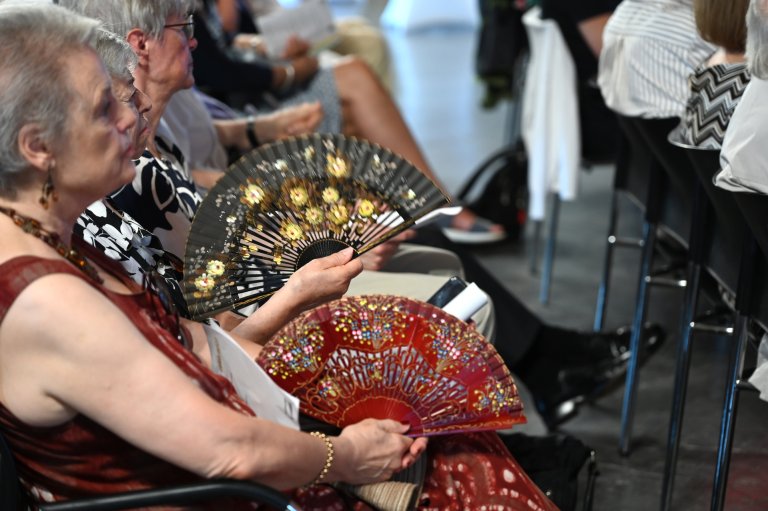 Two women with fans sit in Aachen's Coronation Hall.