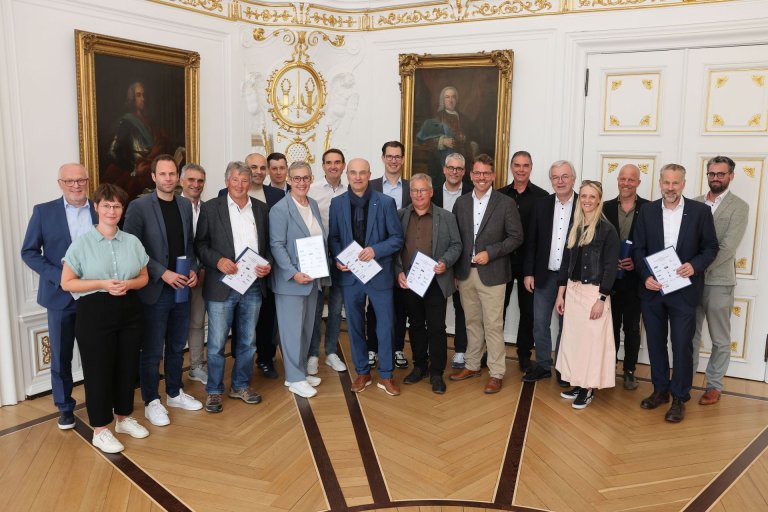 A group of people stand in the White Hall of the town hall