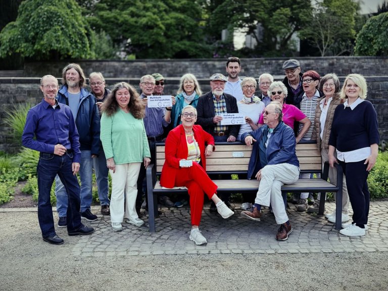 A group of people are standing around a bench.