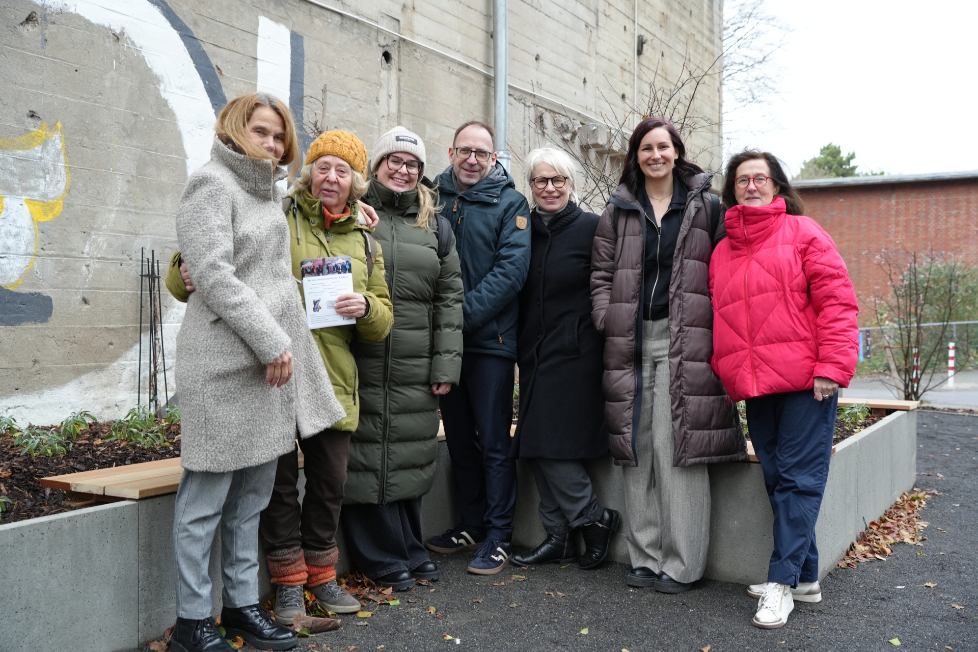 A group of people in front of a bench in front of a bunker facade.