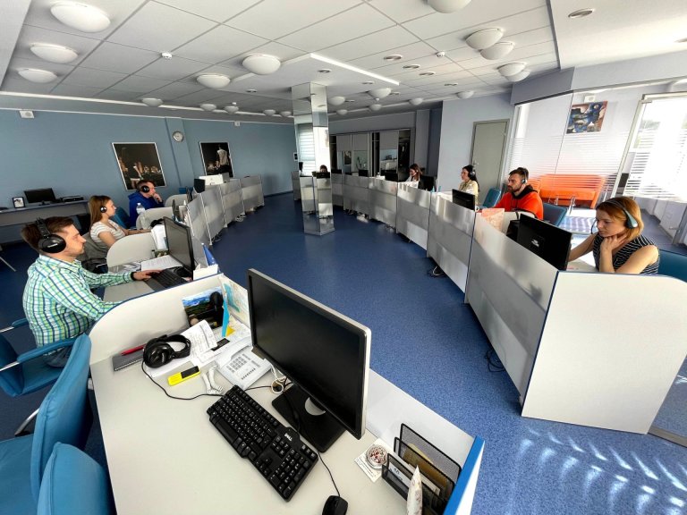 People wearing headsets sit in separate work areas in front of screens