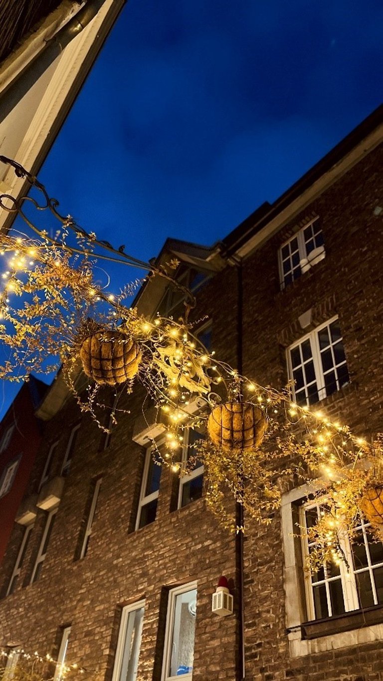 Illuminated decorations hang between two rows of houses