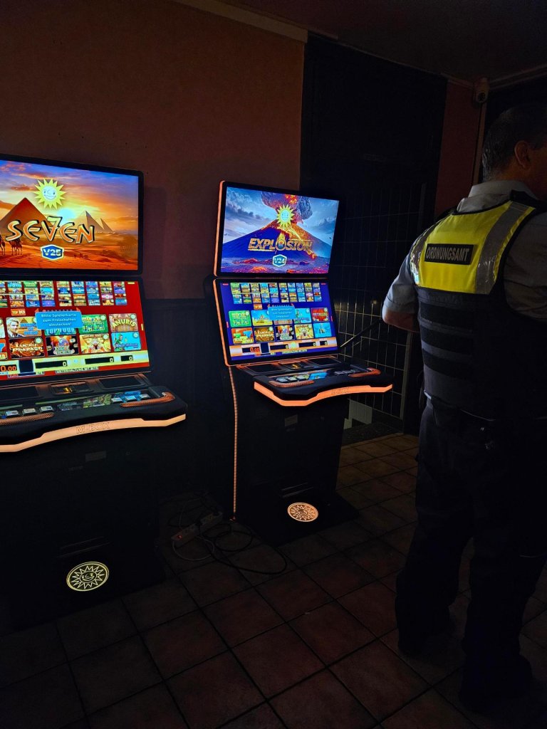 A dark room with slot machines and an employee of the public order office.