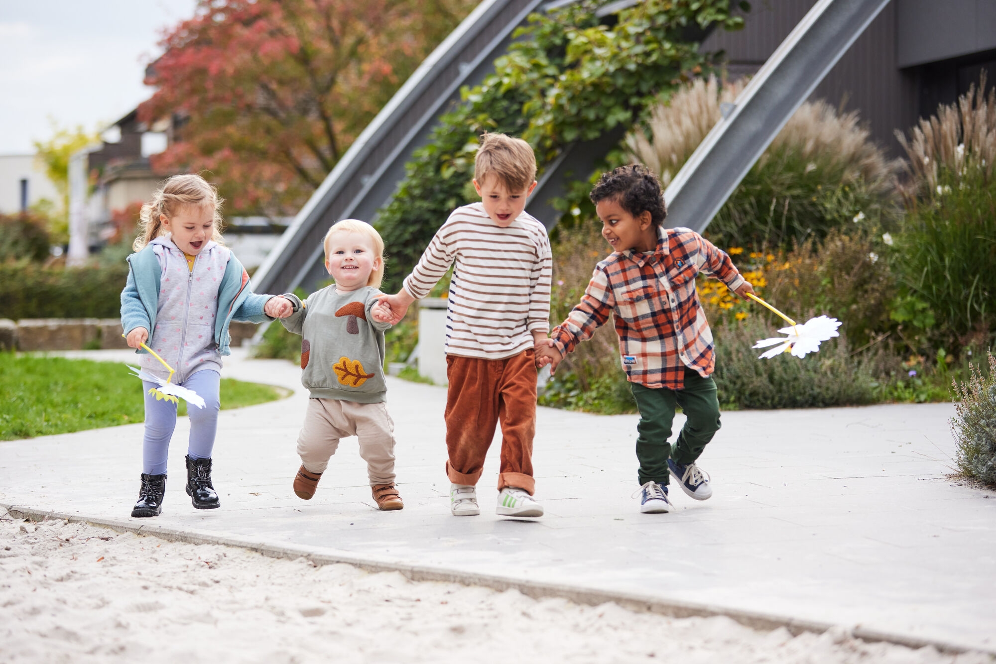 Four toddlers holding hands in the sandpit