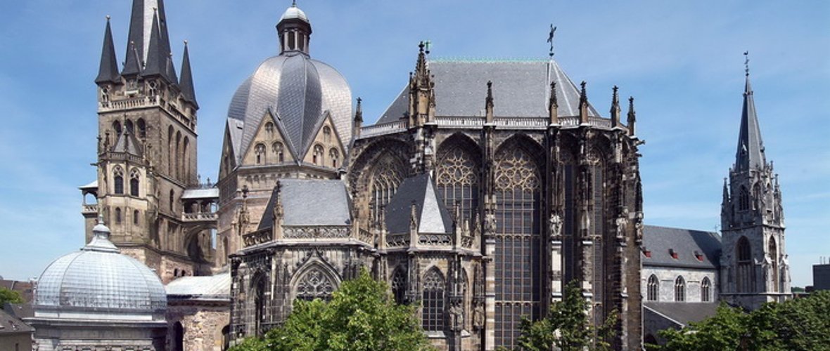 Une vue extérieure de la cathédrale en été. Le soleil brille et les arbres sont verts.