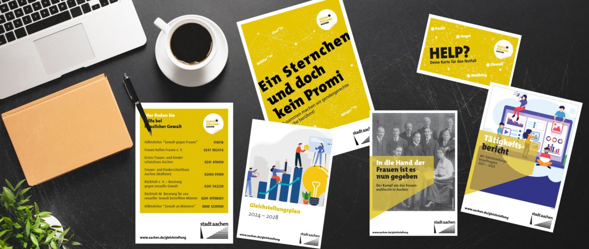 Sur une table, il y a plusieurs brochures et dépliants, à côté d'une tasse de café et d'un ordinateur portable.