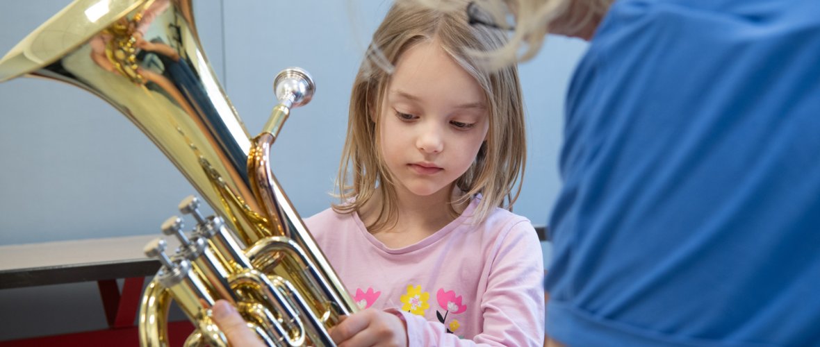 une fille regarde son tuba et l'essaie