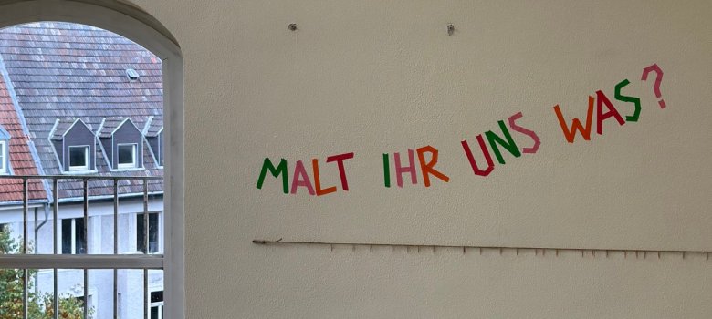 Sur le mur, il est écrit : "Vous nous dessinez quelque chose ?"