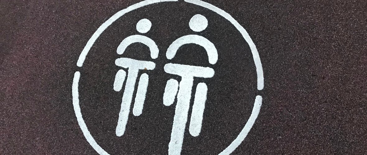 Un anneau blanc avec deux cyclistes représentés de manière abstraite*.