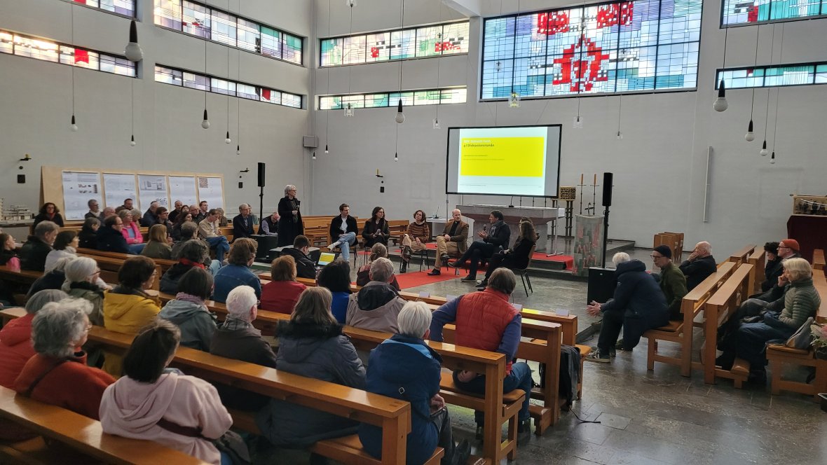 Soirée d'introduction dans une église bien remplie. Au fond, on voit une présentation et le panel de discussion sur l'avenir des bâtiments d'église.