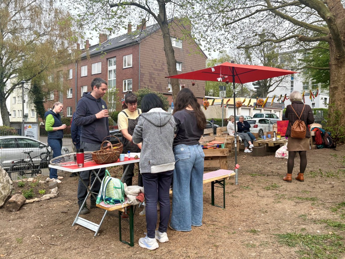 Les membres* d'un groupe de jardinage et les visiteurs en train de bricoler ensemble dans le jardin de l'église. Deux visiteuses sont assises à l'arrière-plan.