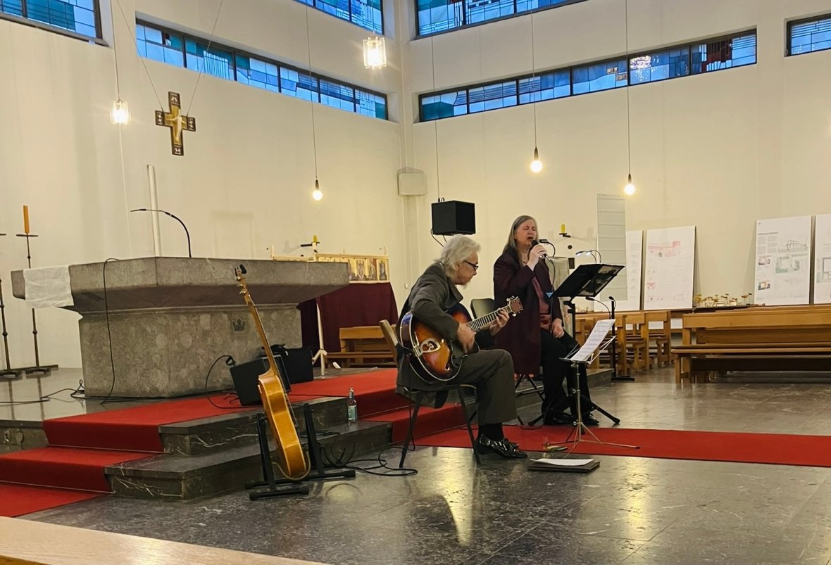Focus sur deux musiciens de jazz* avec des bancs d'église dans l'image. On voit également plusieurs flyers d'événements sur le banc de l'église.
