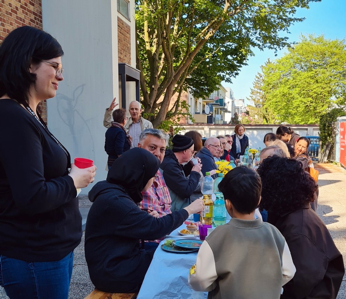 Les enfants sont joyeusement assis avec leurs parents sur un long banc et mangent ensemble devant l'église.