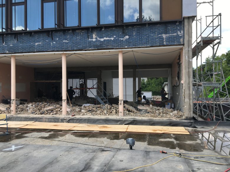 La démolition progresse et met à jour la façade originale en carreaux bleus après la démolition des surfaces partielles du système composite d'isolation thermique.