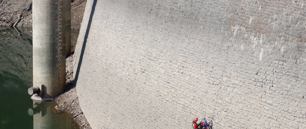 Un exercice de descente en rappel du sauvetage en hauteur ne doit pas toujours se faire vers le haut. On peut tout aussi bien s'entraîner en profondeur. Un barrage est un bon endroit. Un collègue descend en rappel toute la hauteur d'une telle paroi.
