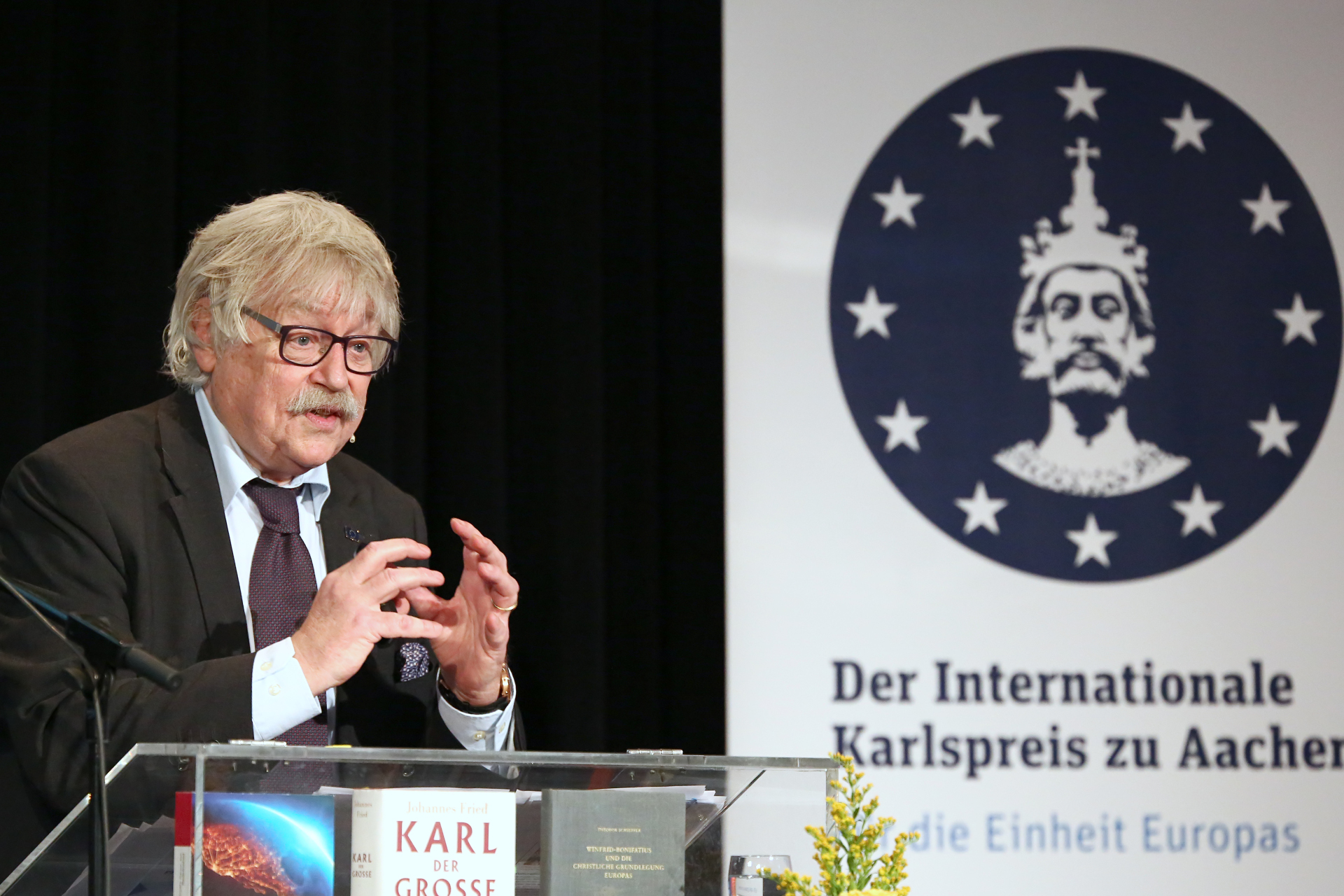 Le professeur Dr. Max Kerner se tient sur un podium, derrière lui la bannière du prix Charlemagne.