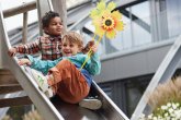 Deux enfants sur un toboggan. Un enfant tient un moulin à vent