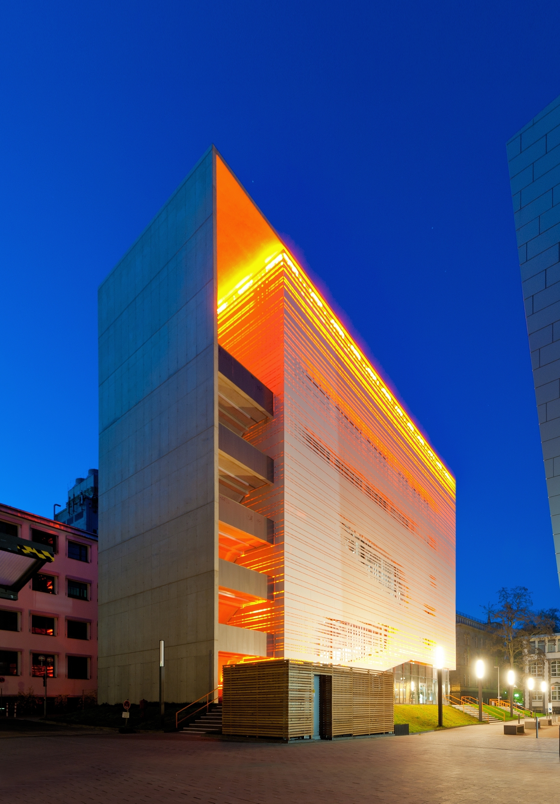 RWTH Aachen Ancienne centrale thermique de la RWTH avec une façade illuminée en orange, photographiée à l'heure bleue.