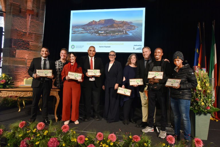 Un groupe de personnes sur une scène avec des panneaux à la main sur lesquels est inscrit un 25.