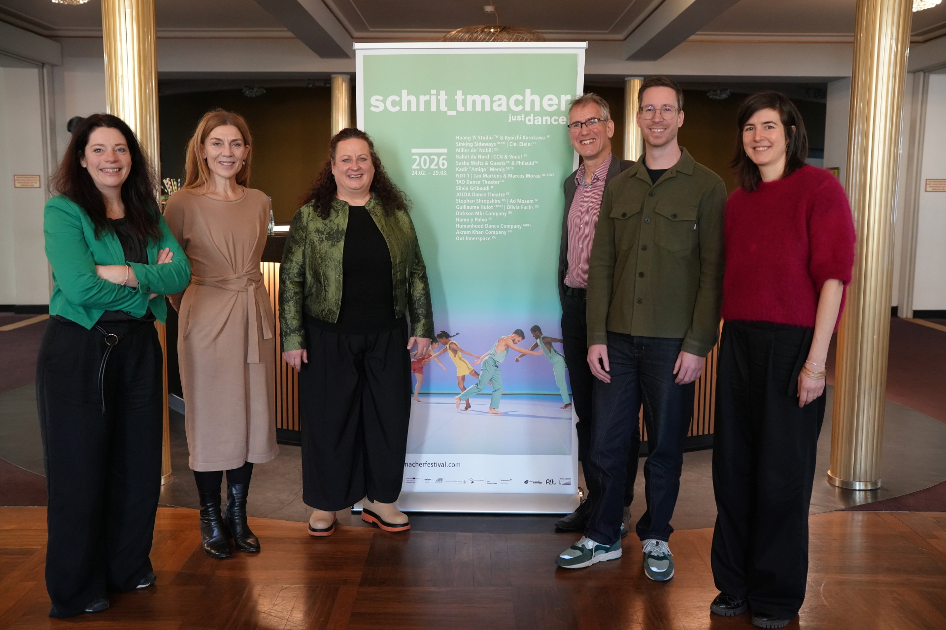 Six personnes se tiennent à côté d'une affiche qui fait la promotion du festival Schrittmacher 2026.