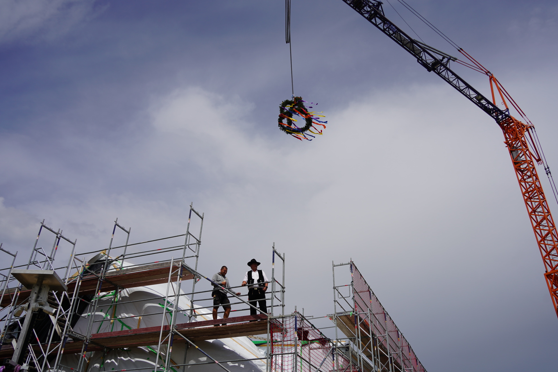Une couronne décorée est suspendue à une grue au-dessus d'un bâtiment.