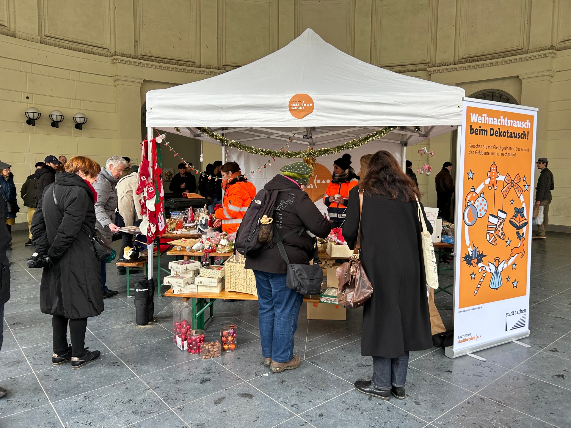 Les visiteurs* lors du troc regardent des articles de Noël.