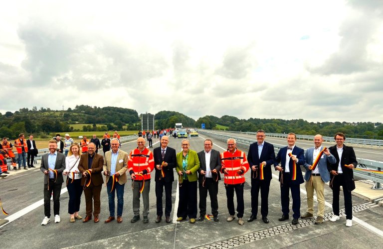 Coupe du ruban sur l'A544 (de gauche à droite). Daniel Scheen-Pauls (député), Annika Fohn (députée), Roger Nießen (maire de la ville de Würselen), Bernhard Brackhues(directeur d'Amand Brückenbau), Dirk Brandenburger (directeur technique de l'Autobahn GmbH de l'État fédéral), Gerhard Rühmkorf (directeur ministériel au ministère fédéral des Transports), Sibylle Keupen (maire de la ville d'Aix-la-Chapelle), Oliver Krischer(ministre des Transports de Rhénanie-du-Nord-Westphalie), Thomas Ganz (directeur de succursale de l'Autobahn GmbH Rheinland), Dr. Tim Grüttemeier (conseiller municipal de la région d'Aix-la-Chapelle), Michael Bayer (directeur général de la CCI d'Aix-la-Chapelle), Marco Herwartz (président de la chambre des métiers d'Aix-la-Chapelle), Yannic Schmitt(directeur général de l'union des métiers d'Aix-la-Chapelle). De nombreuses personnes coupent un ruban.