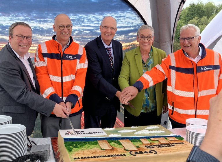 Coupe du gâteau (de gauche à droite ) Oliver Krischer (ministre des transports de la Rhénanie-du-Nord-Westphalie), Dirk Brandenburger (directeur technique de l'Autobahn GmbH de l'État fédéral), DirkBrandenburger (directeur technique de l'Autobahn GmbH de l'État fédéral), Gerhard Rühmkorf (directeur ministériel au ministère fédéral des transports), Sibylle Keupen (maire de la ville d'Aix-la-Chapelle), Thomas Ganz (directeur de succursale de l'Autobahn GmbHRheinland). Des personnes coupent un gâteau.