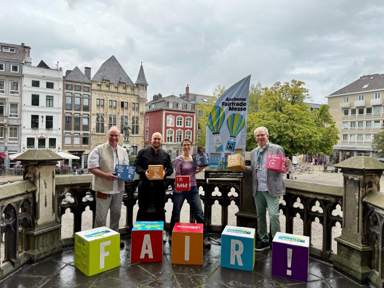 Quatre personnes se tiennent derrière quatre dés sur lesquels est inscrit « FAIR ».